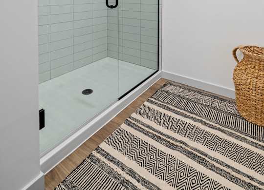 A bathroom with a glass shower door and a wicker basket on the floor.