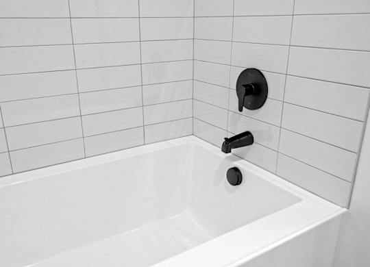 A white bathtub with a black faucet and a black handle.