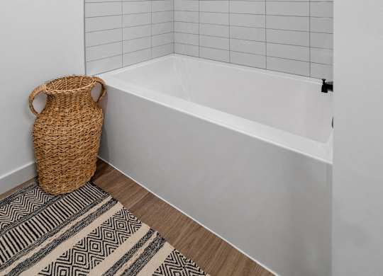 A white bathroom with a white tub and a wicker basket on the floor.