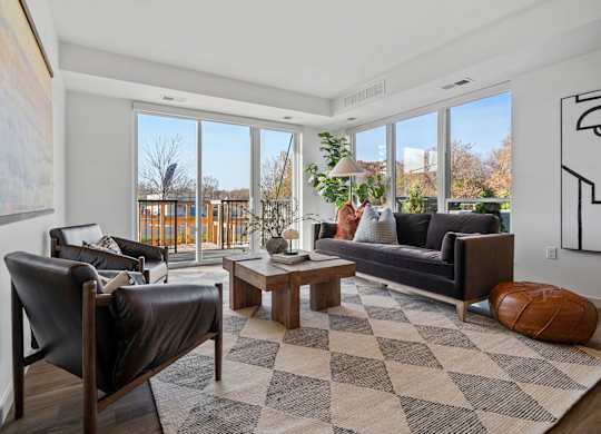 A living room with a black leather chair and a checkered rug.