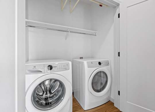 Two white front loading washing machines in a laundry room.