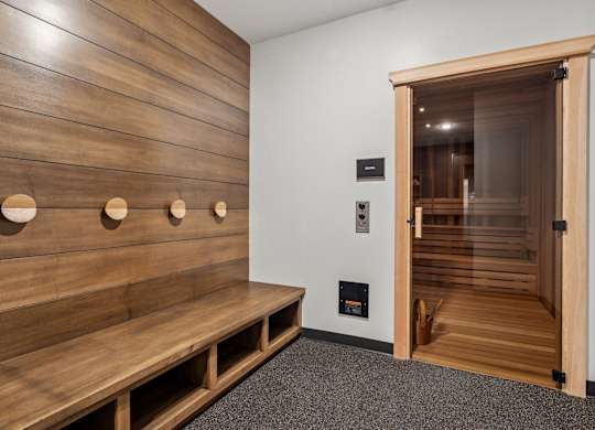 A wooden bench with circular cutouts on the back is in front of a wooden wall.