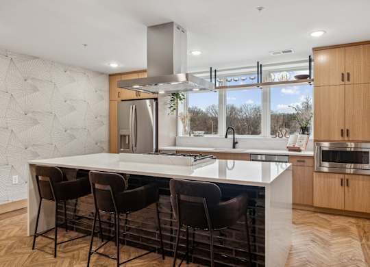 A modern kitchen with a large island and chairs.