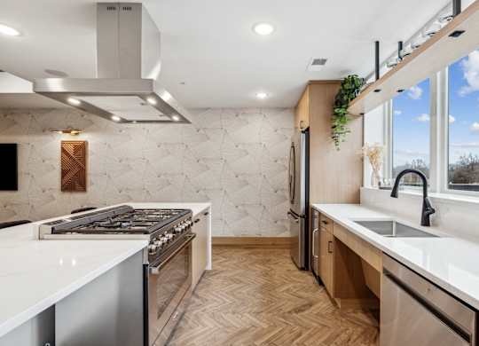 A modern kitchen with a white countertop and wooden flooring.