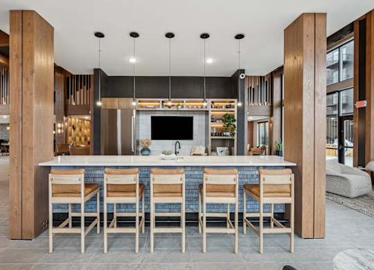 A modern kitchen with a bar area and wooden chairs.