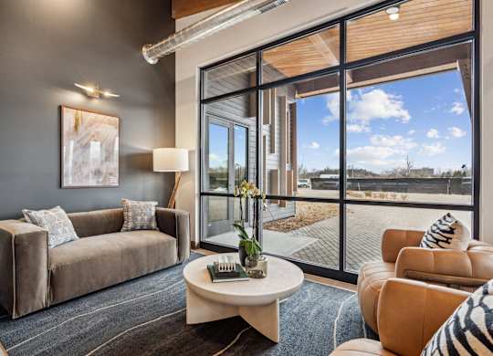 A living room with a grey couch, a coffee table, and a large window.