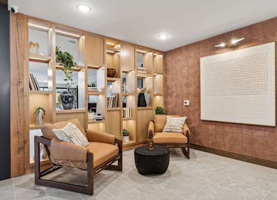 A living room with a brown sofa, a wooden chair, and a large painting on the wall.