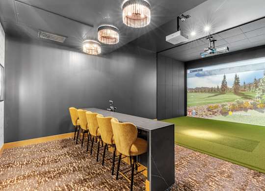 A room with a long table and chairs with a screen at the end of the table.