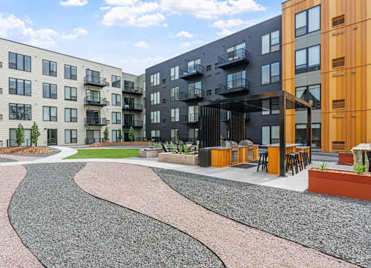 A modern apartment complex with a gravel courtyard in the foreground.