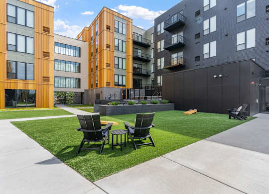 Two chairs are on a lawn in front of a building.