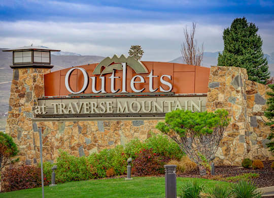 A sign that says Outlets at Traverse Mountain in front of a mountain.