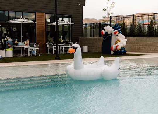 A white inflatable duck is floating in a pool.