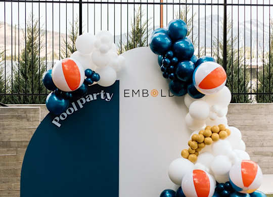 A pool party balloon arch with the words
