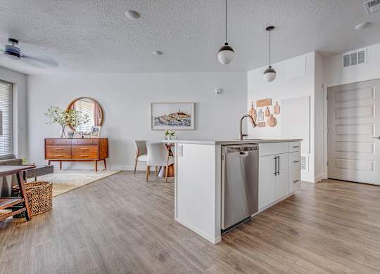 A modern kitchen with white cabinets and a wooden floor.