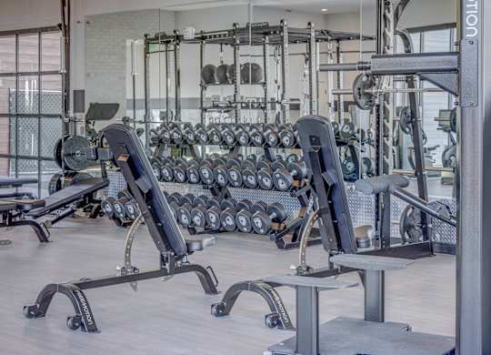 A gym with a variety of equipment including dumbbells and weight machines.