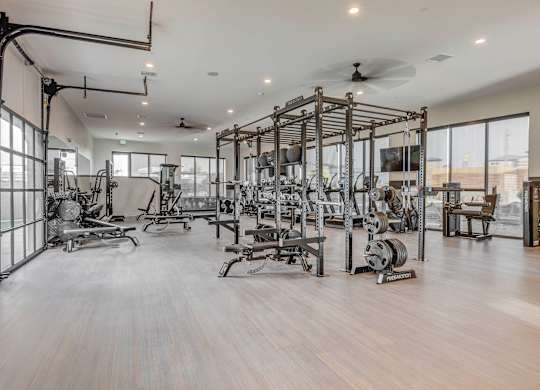A spacious gym with a variety of equipment and a ceiling fan.