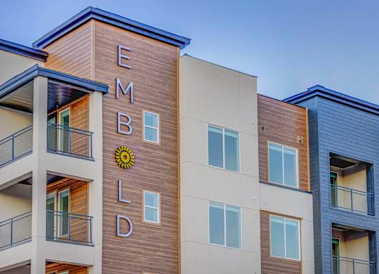 The image shows a modern building with the name "EMBLD" on its facade.