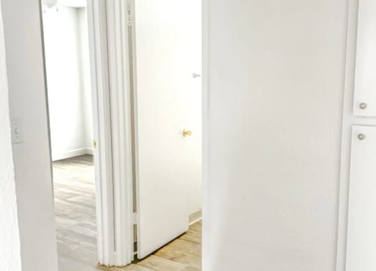 A white door is open to a room with a wooden floor.