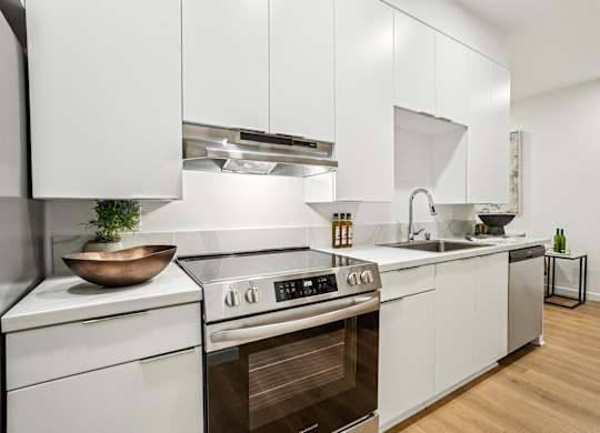 A modern kitchen with white cabinets and stainless steel appliances.