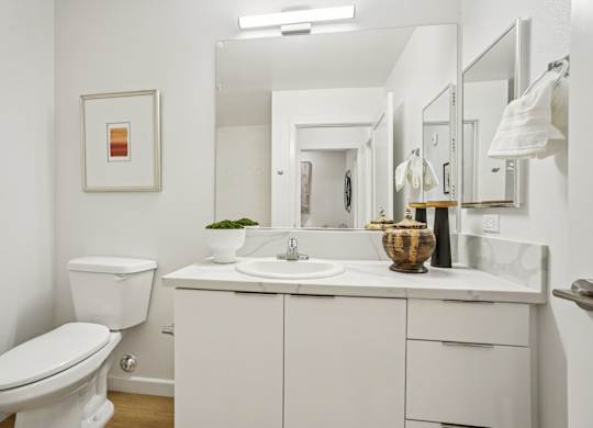A white bathroom with a toilet, sink, and mirror.
