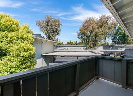 A balcony with a view of a parking lot and trees.