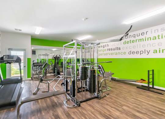 A gym with a green wall and a variety of equipment. at Chaparral Apartments, California