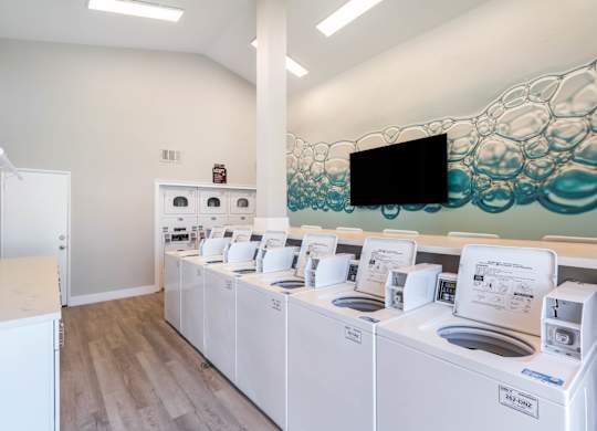 A row of washing machines are lined up in a laundromat at Chaparral Apartments, California