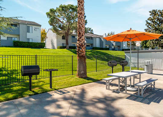 A bright orange umbrella is on a table outside a building at Chaparral Apartments, Palmdale 93551