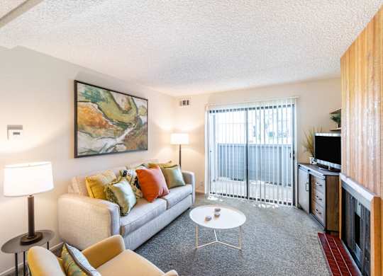A living room with a couch, chairs, and a painting on the wall at Chaparral Apartments, California