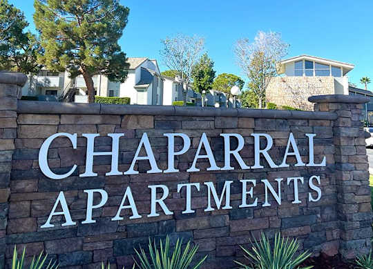 A sign that says Chaparral Apartments in front of some houses at Chaparral Apartments, California, 93551