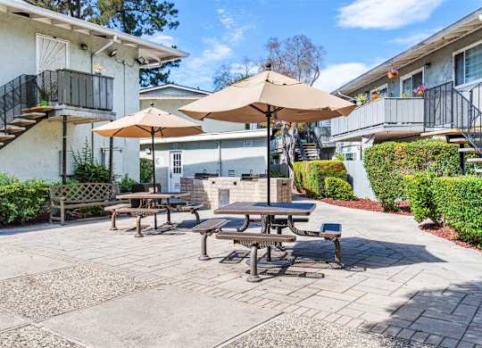 A patio with tables and chairs and umbrellas.