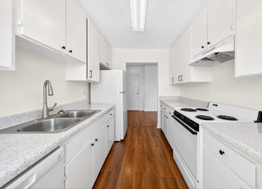 A kitchen with white cabinets and a wooden floor.