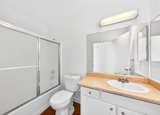 A white bathroom with a toilet, sink, and mirror.