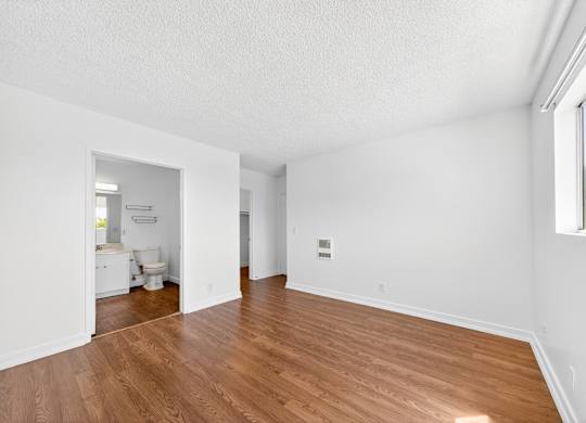 A large empty room with wooden floors and white walls.