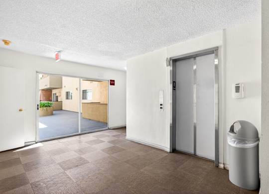 A room with a trash can and a door.