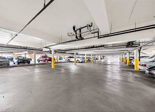 A parking garage with cars parked in yellow lines.