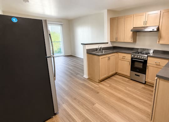 A kitchen with wooden cabinets and a black fridge.