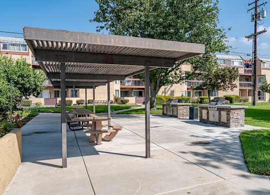 A concrete pavement with a wooden pergola and benches at Oak Park Apartments, Monrovia, 91016