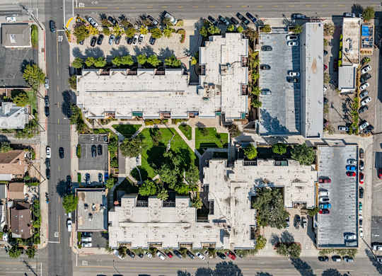 A large white building is surrounded by a parking lot and other buildings at Oak Park Apartments, Monrovia, 91016