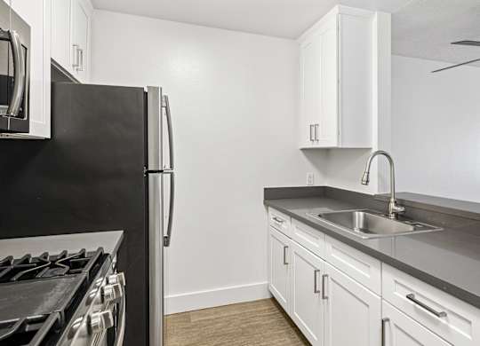 A kitchen with a black fridge and white cabinets.