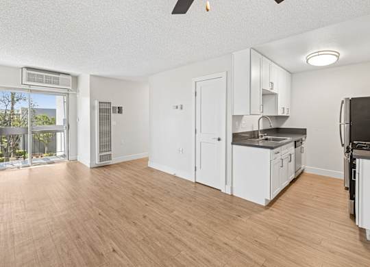 A kitchen with white cabinets and a wooden floor.