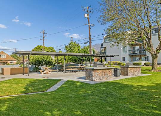 A sunny day at a park with a picnic table and a stone wall.