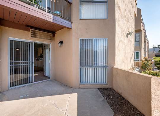 A tan building with a balcony and a gate at Oak Park Apartments, Monrovia, 91016