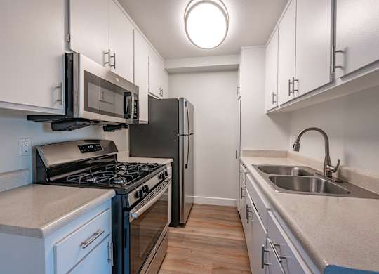 A kitchen with a stove, microwave, and refrigerator at Oak Park Apartments, Monrovia, 91016