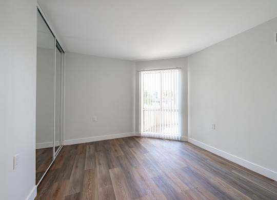 A room with wooden floors and a window with blinds at Oak Park Apartments, Monrovia, 91016