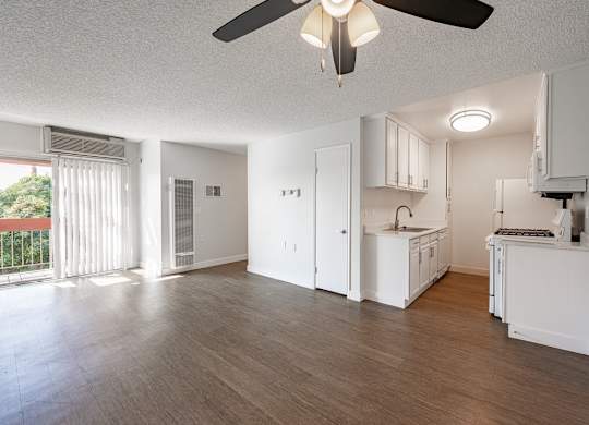A spacious kitchen with white cabinets and a ceiling fan at Oak Park Apartments, Monrovia, 91016
