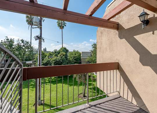 A balcony with a metal railing and a lamp post at Oak Park Apartments, Monrovia, 91016