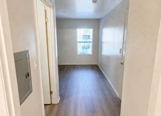 A long hallway with wood floors and white walls.