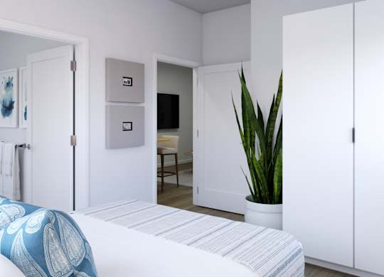 A white bedroom with a bed, a chair, a plant, and a painting on the wall.