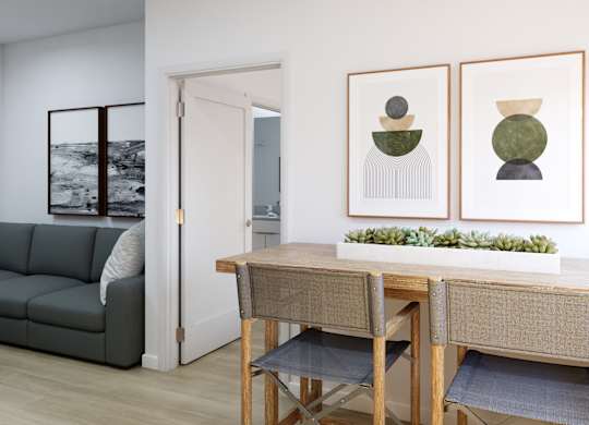 A room with a grey couch, a wooden table and two framed pictures on the wall.
